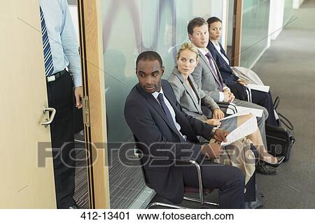 Stock Image - Business people sitting in waiting area. Fotosearch