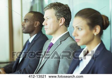 Stock Image - Business people sitting in waiting area. Fotosearch