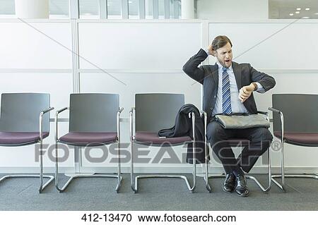 Businessman checking wristwatch in waiting area View Large Photo Image Stock Image - Businessman checking wristwatch in waiting area. Fotosearch