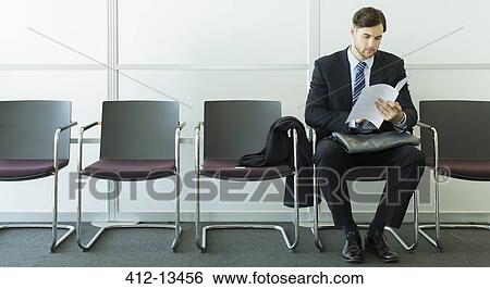 Stock Photograph - Businessman sitting in waiting area. Fotosearch