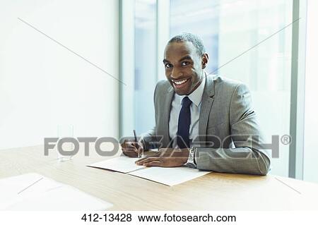 Businessman smiling at conference table View Large Photo Image Stock Photo - Businessman smiling at conference table. Fotosearch