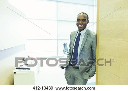 Businessman smiling in office View Large Photo Image Stock Photo - Businessman smiling in office. Fotosearch