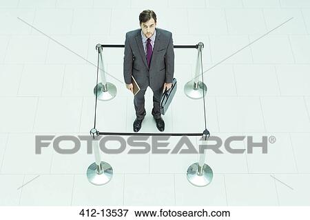 Businessman standing in roped-off square View Large Photo Image Stock Photo - Businessman standing in roped-off square. Fotosearch