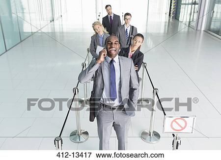Businessman talking on cell phone in line View Large Photo Image Stock Photo - Businessman talking on cell phone in line. Fotosearch