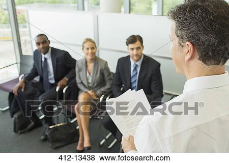 Businessman talking to colleagues in office View Large Photo Image Stock Photo - Businessman talking to colleagues in office. Fotosearch