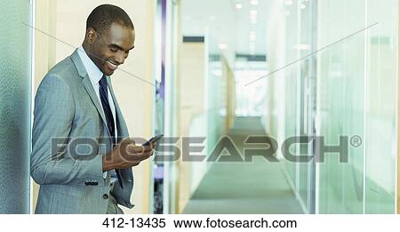 Stock Photography - Businessman using cell phone in office. Fotosearch