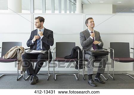 Businessmen adjusting ties in waiting area View Large Photo Image Stock Image - Businessmen adjusting ties in waiting area. Fotosearch
