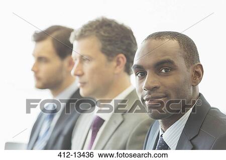 Stock Photograph - Businessmen sitting in office. Fotosearch