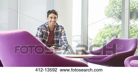 Stock Image - Man using cell phone in lounge. Fotosearch