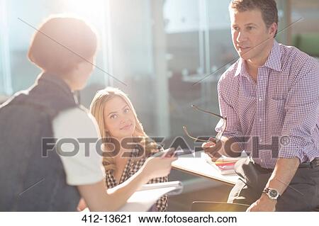 Stock Image - Professor and university students talking in classroom. Fotosearch