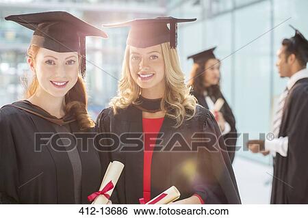 Stock Photograph - Smiling graduates holding diplomas. Fotosearch