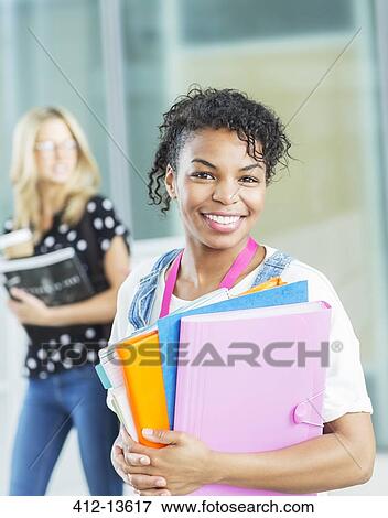 Stock Photo - Smiling university student carrying folders. Fotosearch