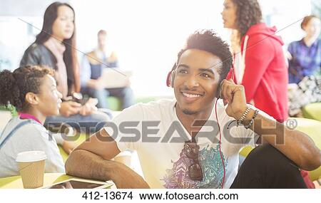 University student listening to headphones in lounge View Large Photo Image Picture - University student listening to headphones in lounge. Fotosearch