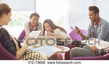 Stock Photograph - University students using technology in lounge. Fotosearch