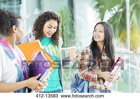 Stock Image - University students walking with books and coffee. Fotosearch