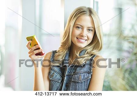Woman using cell phone at window View Large Photo Image Stock Photo - Woman using cell phone at window. Fotosearch