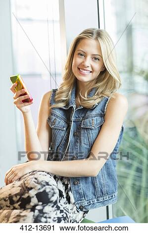 Woman using cell phone by window View Large Photo Image Stock Image - Woman using cell phone by window. Fotosearch