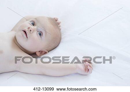 Stock Photo - Baby laying on bed. Fotosearch