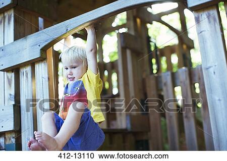 Stock Image - Boy playing on playset outdoors. Fotosearch