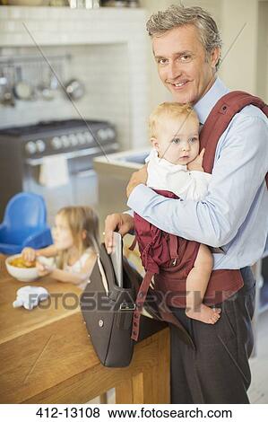 Stock Photo - Businessman carrying baby in kitchen. Fotosearch