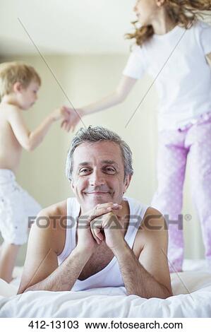 Children jumping on bed around father View Large Photo Image Stock Image - Children jumping on bed around father. Fotosearch