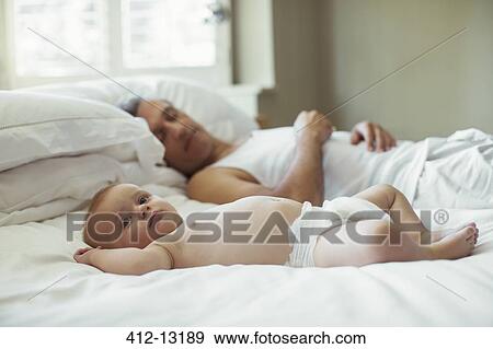 Stock Photo - Father and baby laying on bed. Fotosearch