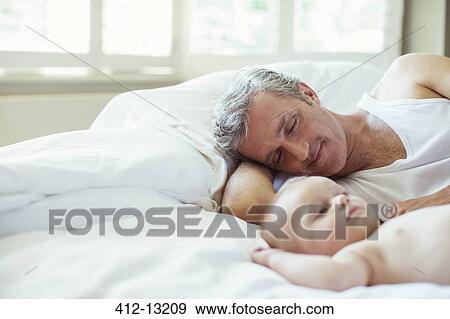 Stock Photo - Father and baby laying on bed. Fotosearch