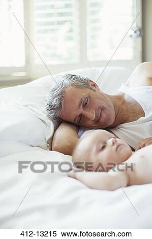 Father and baby laying on bed View Large Photo Image Stock Photography - Father and baby laying on bed. Fotosearch