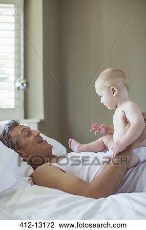 Father and baby relaxing on bed View Large Photo Image Stock Image - Father and baby relaxing on bed. Fotosearch