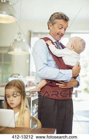 Stock Image - Father and children in kitchen. Fotosearch