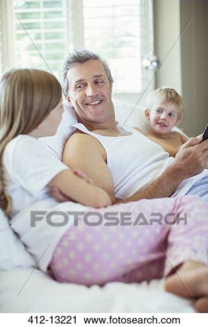 Father and children relaxing on bed View Large Photo Image Stock Image - Father and children relaxing on bed. Fotosearch