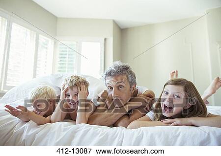 Father and children relaxing on bed View Large Photo Image Stock Photo - Father and children relaxing on bed. Fotosearch