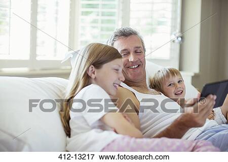 Father and children using digital tablet on bed View Large Photo Image Stock Photo - Father and children using digital tablet on bed. Fotosearch