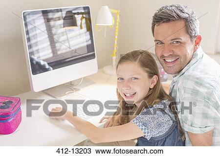 Stock Image - Father and daughter using computer together. Fotosearch