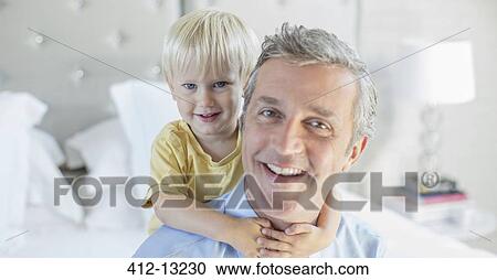 Stock Image - Father and son hugging on bed. Fotosearch