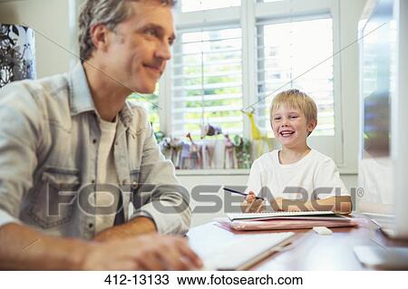 Stock Image - Father and son working in home office. Fotosearch
