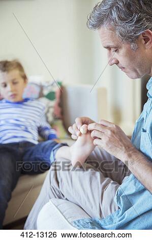 Stock Photograph - Father bandaging son's toe. Fotosearch