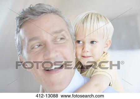 Stock Photo - Father carrying toddler son piggyback. Fotosearch
