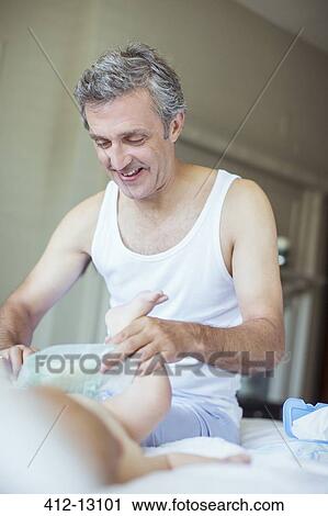 Stock Image - Father changing baby's diaper. Fotosearch