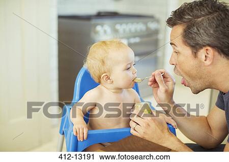 Father feeding baby in high chair View Large Photo Image Stock Image - Father feeding baby in high chair. Fotosearch