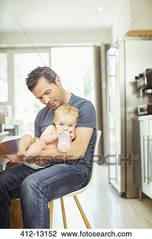 Father feeding baby in kitchen View Large Photo Image Stock Image - Father feeding baby in kitchen. Fotosearch