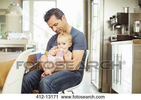 Father feeding baby in kitchen View Large Photo Image Stock Image - Father feeding baby in kitchen. Fotosearch