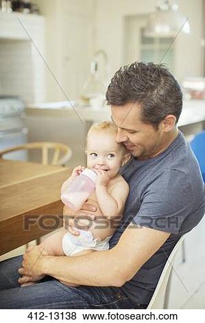 Father feeding baby in kitchen View Large Photo Image Stock Photo - Father feeding baby in kitchen. Fotosearch