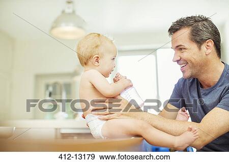 Father feeding baby in kitchen View Large Photo Image Stock Photo - Father feeding baby in kitchen. Fotosearch