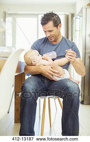 Stock Photo - Father feeding baby in kitchen. Fotosearch