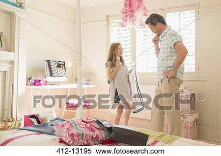 Stock Photography - Father helping daughter pick clothing. Fotosearch