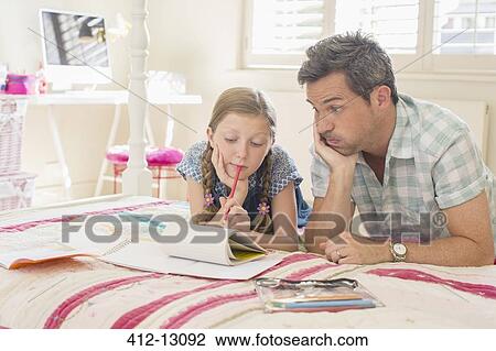 Stock Image - Father helping daughter with homework. Fotosearch