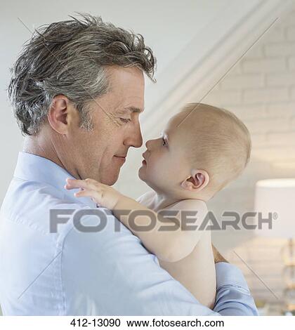 Stock Image - Father holding baby in arms. Fotosearch