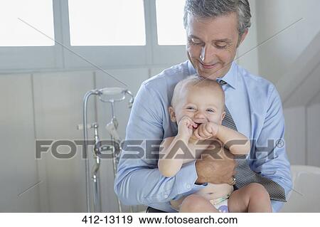 Stock Photo - Father holding baby in bathroom. Fotosearch
