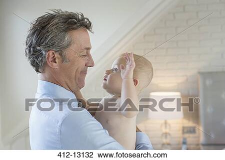 Father holding baby in bedroom View Large Photo Image Stock Image - Father holding baby in bedroom. Fotosearch